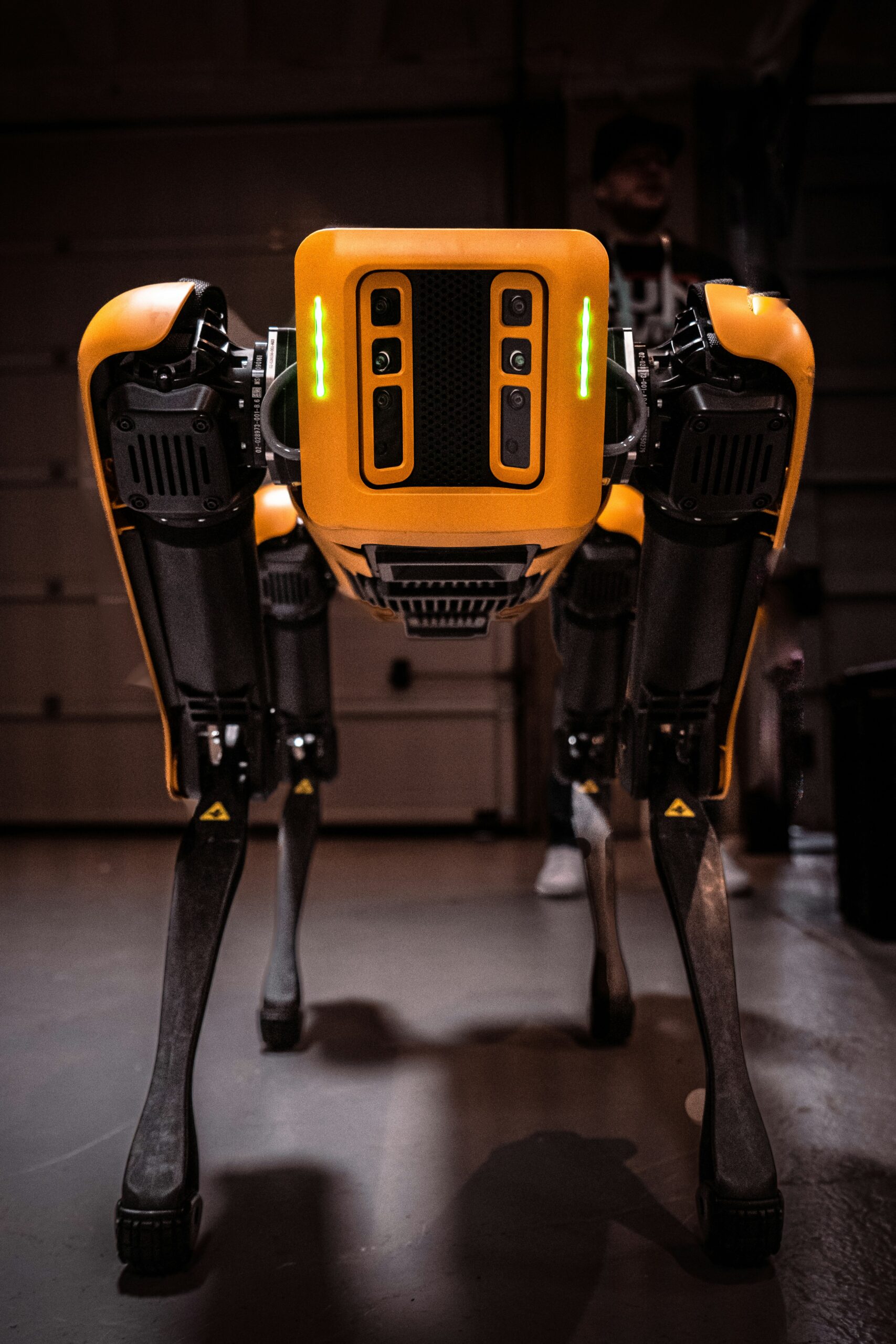 Fotografia de robô inteligente da Boston Dynamics, nas cores amarelo e preto, utilizado para monitoramento e coleta de dados, parado em uma garagem.